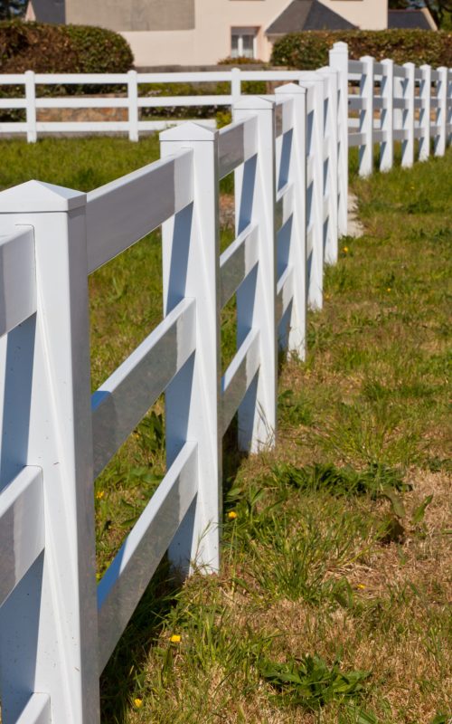 Country White Plastic Fence Country New White Plastic Fence after Mowing. Sunny day